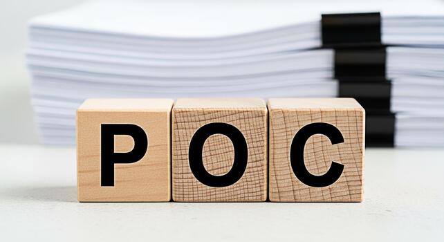 Wooden blocks displaying POC on a white table with a stack of papers in the background representing proof of concept and the importance of documentation in business and project management photo