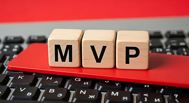 de madera bloques ortografía mvp descansando en un rojo tarjeta encima un negro ordenador portátil teclado simbolizando un mínimo viable producto en un tecnología puesta en marcha ambiente transporte innovación y ágil desarrollo foto