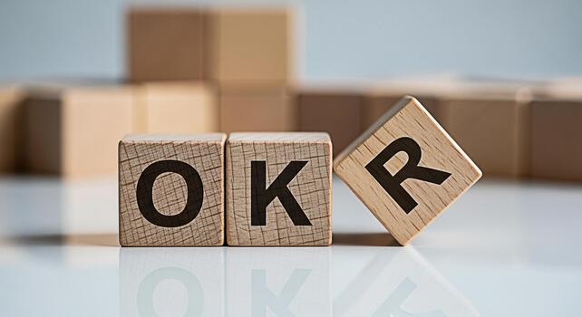 Wooden blocks displaying OKR acronym on a reflective surface representing objectives and key results in a business setting symbolizing goal setting and strategic planning for success photo
