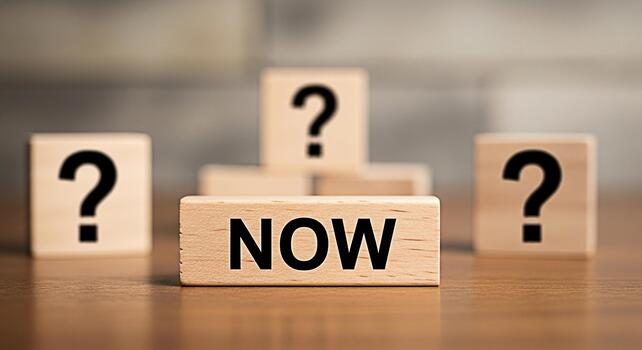 Wooden blocks displaying NOW amidst question marks on a reflective surface emphasizing urgency and decisionmaking in a blurred background creating a sense of immediacy and opportunity photo