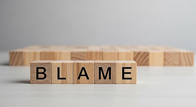 Wooden blocks spelling out BLAME on a white surface conveying a sense of responsibility and accountability in a neutral corporate environment symbolizing conflict resolution and problemsolving photo
