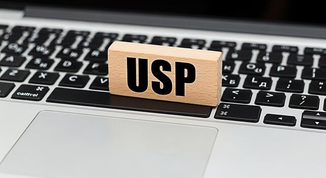 Wooden block displaying USP resting on a laptop keyboard in a modern office setting symbolizing unique selling proposition and business strategy for competitive advantage and market differentiation photo