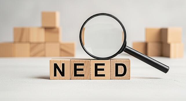 Magnifying glass examining the word NEED spelled out with wooden blocks on a white surface symbolizing investigation and problemsolving in a minimalist and focused environment photo