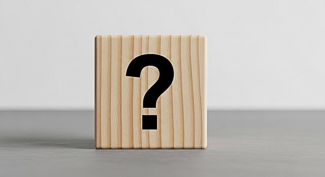 Wooden block displaying a question mark on a gray surface symbolizing uncertainty and inquiry in a minimalist studio setting evoking curiosity and the search for answers photo