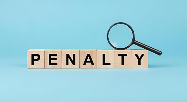 Magnifying glass inspecting wooden blocks spelling PENALTY on a blue background representing scrutiny and consequences creating a serious and cautionary mood in a business or legal context photo