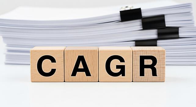 Wooden blocks displaying CAGR with a stack of documents in the background representing compound annual growth rate in a financial analysis context conveying a sense of business planning and strategic photo
