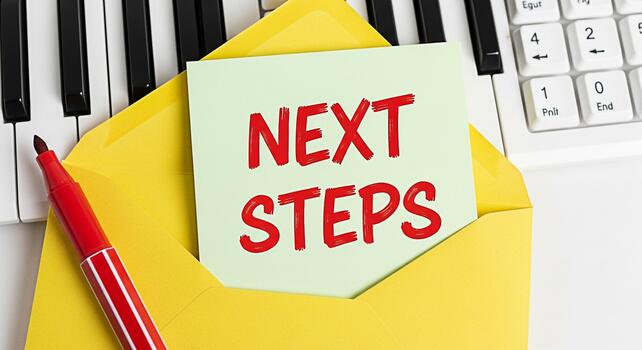 Bright yellow envelope displaying Next Steps note surrounded by piano keys and a red marker symbolizing planning and forwardthinking in a creative and musical environment photo