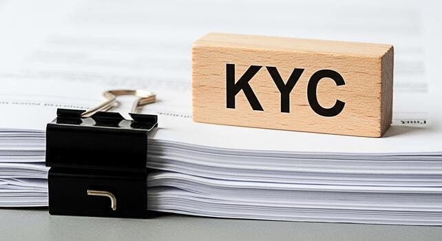 KYC Know Your Customer compliance displayed on a wooden block resting on a stack of documents with a binder clip symbolizing regulatory adherence and risk management in a business environment photo