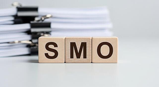 Wooden blocks spelling SMO on a white desk with a stack of documents representing social media optimization and digital marketing strategies for business growth and online presence conveying a profess photo