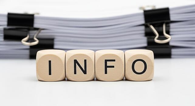 Wooden blocks spelling INFO in front of a stack of paperwork suggesting information overload and the need for data management in a busy office environment conveying a sense of organization and efficie photo