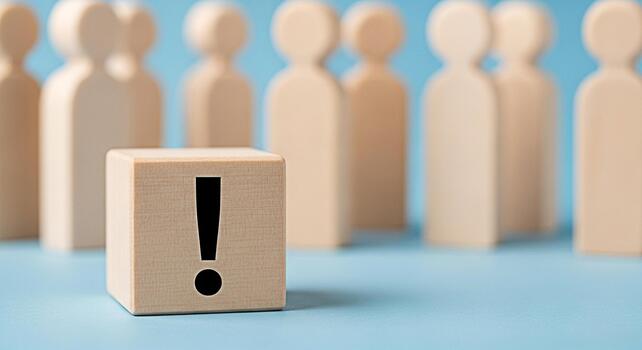 Wooden block displaying an exclamation point stands out among a group of wooden figures on a blue surface symbolizing attention to detail problemsolving and the importance of standing out from the cro photo