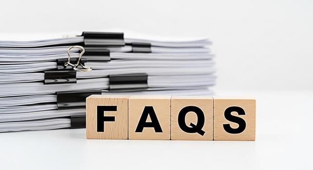Stack of documents with black clips and wooden blocks spelling FAQs on a white table representing frequently asked questions and information resources in a clean and organized environment photo