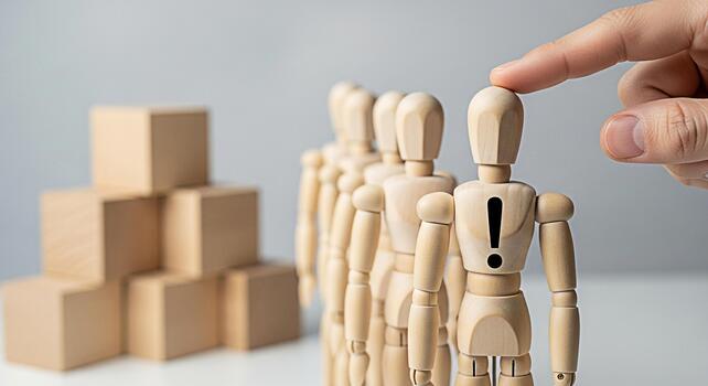 Wooden mannequin with an exclamation mark on its chest being selected by a finger in a studio setting symbolizing choice individuality and standing out from the crowd with a focus on uniqueness photo