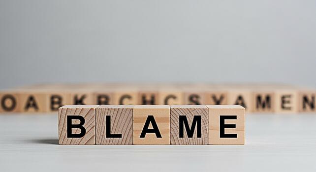 Wooden blocks spelling out the word BLAME on a white surface conveying a concept of responsibility and accountability in a neutral setting highlighting the potential for conflict and negative conseque photo