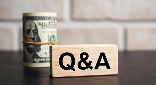 Roll of US currency and a wooden block with QA on a dark table against a brick wall symbolizing financial questions and answers investment advice and economic discussions in a professional setting photo