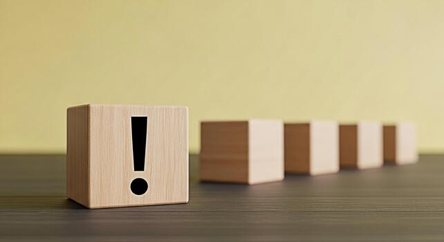 Wooden block displaying an exclamation point stands out in a row on a dark wooden table against a light yellow wall symbolizing urgency attention and the importance of problemsolving photo