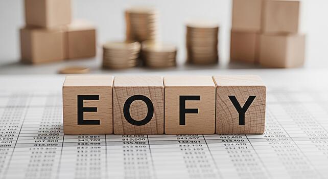 Wooden blocks spelling EOFY resting on a financial report symbolizing the end of the fiscal year and the importance of financial planning with stacks of coins in the background conveying prosperity photo