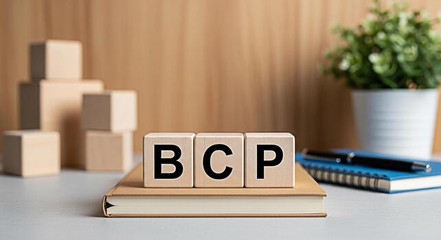 Wooden blocks displaying BCP on a book in a bright office setting symbolizing Business Continuity Planning and resilience with a focus on preparedness and strategic management for successful operation photo