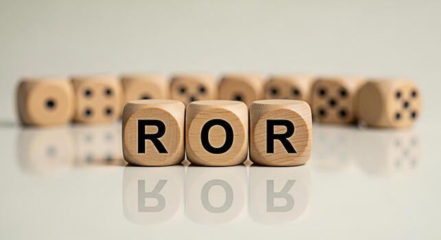Wooden dice spelling ROR on a reflective surface representing the concept of Rate of Return in a financial setting conveying a sense of investment and financial analysis with a neutral background photo