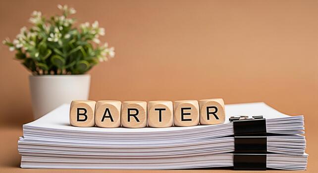 Wooden blocks spelling BARTER resting on a stack of papers in a neutral setting symbolizing trade exchange and the concept of alternative economic systems with a focus on business and finance photo