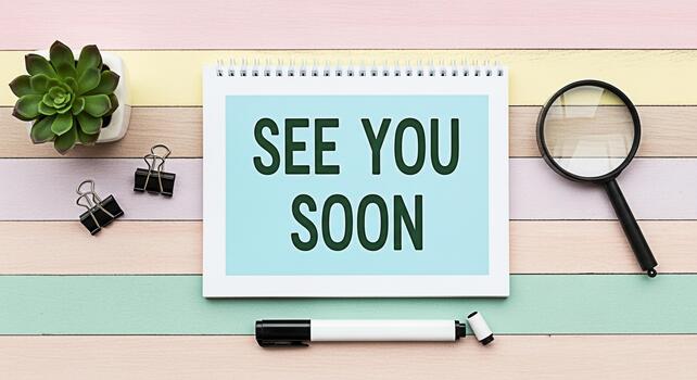 Topdown view of a notepad displaying See You Soon on a pastel striped desk accompanied by a succulent binder clips a marker and a magnifying glass conveying a farewell and anticipation mood photo