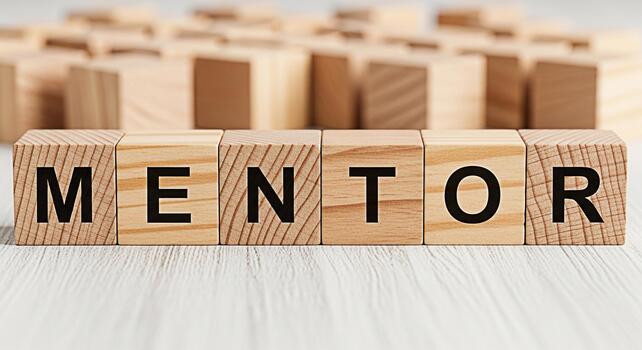 Wooden blocks spelling MENTOR on a white wooden surface representing guidance and support in a learning environment fostering a positive and encouraging atmosphere for growth and development photo