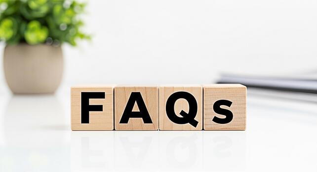 Wooden blocks spelling FAQs on a white table with a plant in the background representing frequently asked questions and providing information and support in a clean and professional environment photo