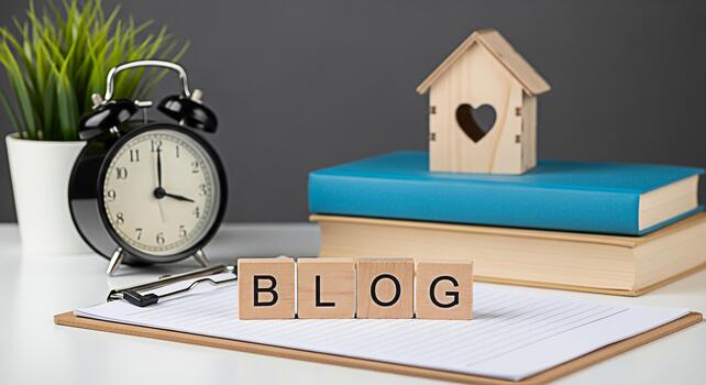 Wooden blocks spelling BLOG on a clipboard in a bright organized workspace with books a house model and a clock representing content creation and the importance of time management for bloggers photo