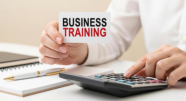 Closeup of a hand holding a business training card while calculating on a calculator in a bright office setting emphasizing the importance of professional development and financial literacy photo