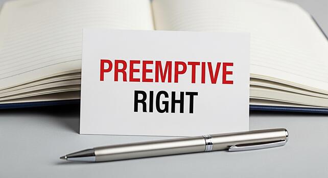 Closeup of a card displaying Preemptive Right next to an open notebook and pen on a gray surface symbolizing legal foresight and strategic planning in a business or financial context photo