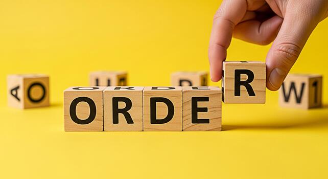 Hand completing the word ORDER with wooden blocks on a bright yellow background symbolizing organization structure and control in business and personal life promoting efficiency and success photo