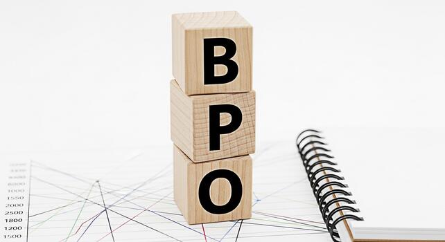 Wooden blocks spelling BPO resting on a financial chart with a notepad symbolizing business process outsourcing and efficient operations in a clean modern office environment conveying professionalism photo