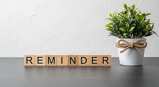 Reminder message displayed on wooden blocks with a potted plant on a gray table against a white wall creating a calm and organized workspace atmosphere photo