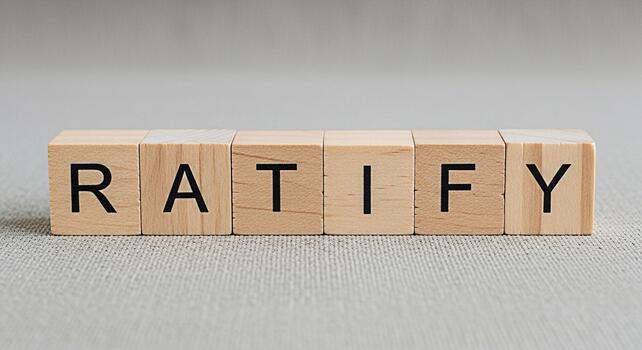 Wooden blocks spelling RATIFY on a textured gray surface representing agreement and approval in a neutral setting conveying a sense of validation and legal confirmation photo