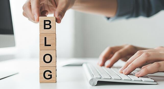 Person arranging wooden blocks spelling BLOG while typing on a keyboard in a bright minimalist office symbolizing online content creation and digital marketing success photo