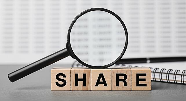 Magnifying glass examining the word SHARE spelled out with wooden blocks on a desk symbolizing investment analysis and the importance of sharing information in a financial or business context photo