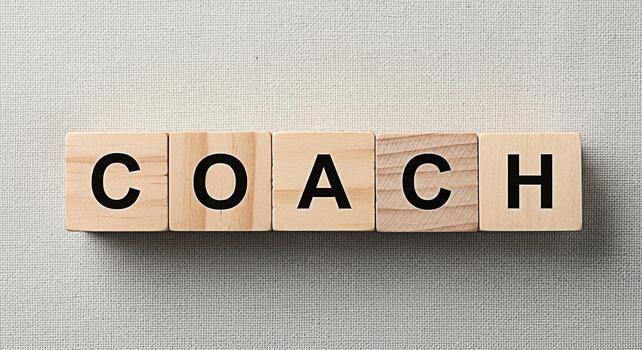 Wooden blocks spelling COACH on a textured surface representing guidance and support symbolizing mentorship and professional development in a neutral and minimalist setting conveying a sense of clarit photo
