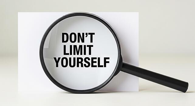 Magnifying glass revealing the message Dont Limit Yourself on a white card in a bright studio setting symbolizing selfimprovement motivation and the power of positive thinking photo