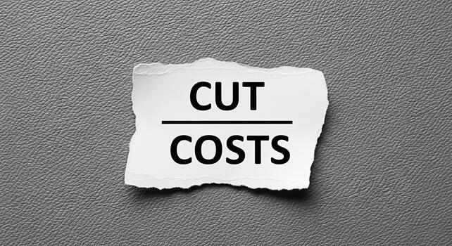 Torn paper with Cut Costs text on a gray textured background symbolizing financial savings and budget reduction in a challenging economic environment conveying a sense of urgency and fiscal responsibi photo