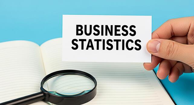 Hand holding a card with Business Statistics over an open notebook with a magnifying glass on a blue background symbolizing analysis research and datadriven decisionmaking in a professional setting photo