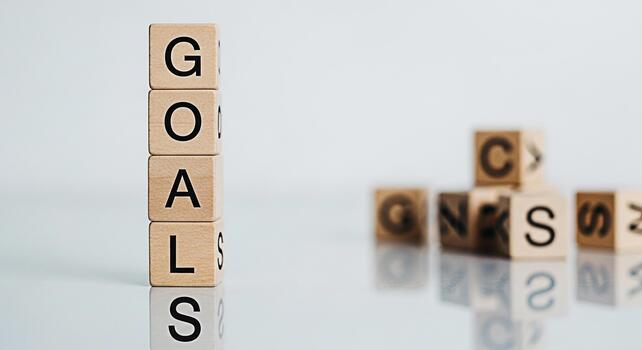 Wooden blocks spelling GOALS stacked high on a reflective surface symbolizing ambition and achievement in a minimalist setting inspiring motivation and focus for personal and professional success photo