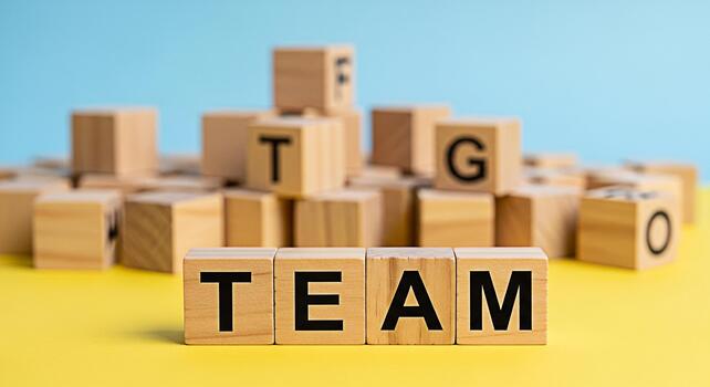 Wooden blocks spelling TEAM on a yellow surface against a blue background symbolizing collaboration unity and the power of teamwork in achieving common goals with a positive and supportive atmosphere photo