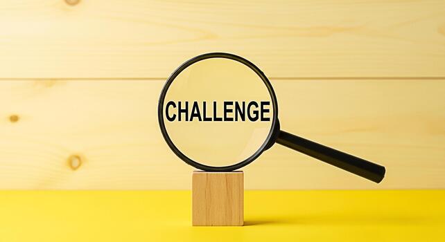 Magnifying glass focusing on the word Challenge on a wooden block against a bright yellow background symbolizing problemsolving opportunity and the importance of critical thinking and analysis photo