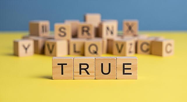 Wooden blocks spelling TRUE on a yellow surface with other letter blocks in the background conveying a message of honesty integrity and the importance of truth in communication and relationships photo