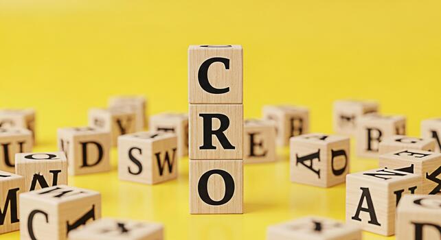 Wooden blocks spelling out CRO standing tall among scattered alphabet blocks on a vibrant yellow surface symbolizing conversion rate optimization and a focused strategic approach to business growth photo
