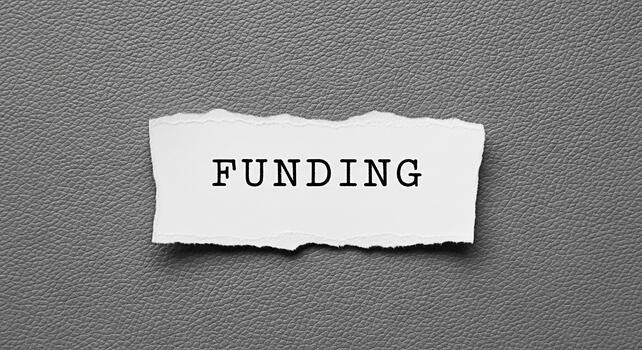 Torn paper displaying the word FUNDING on a textured gray background symbolizing financial support and investment opportunities creating a sense of urgency and importance for business growth and devel photo