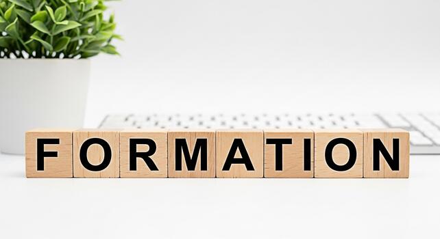 Wooden blocks spelling FORMATION on a white desk with a keyboard and potted plant symbolizing structure organization and the building blocks of success in a clean modern workspace photo