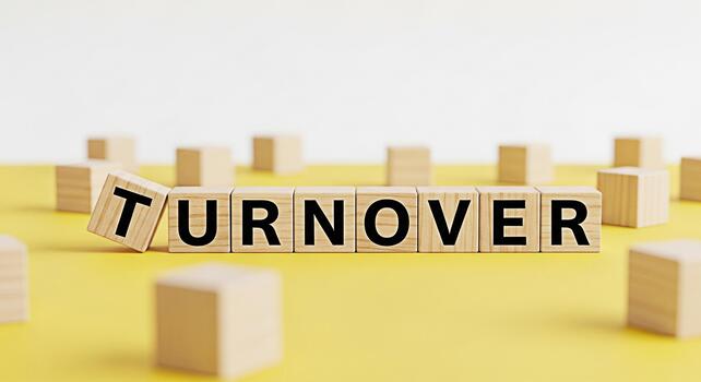 Wooden blocks spelling Turnover on a yellow surface symbolizing business challenges and change with a focus on the concept of employee retention and company performance in a competitive environment photo