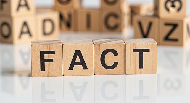 Wooden blocks spelling the word FACT on a reflective surface surrounded by blurred alphabet blocks conveying a sense of truth knowledge and the importance of factual information in a learning environm photo