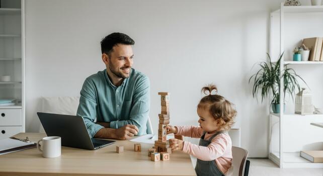Man working on laptop while child plays with blocks table photo